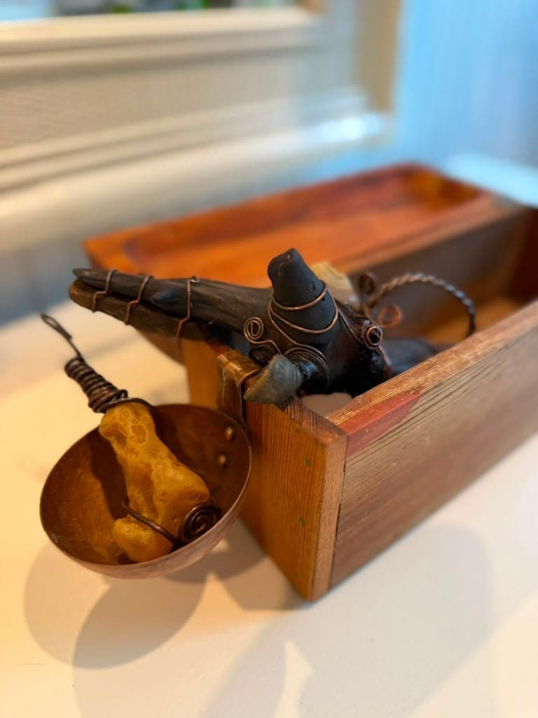 A hand-carved wand and a copper scrying bowl by Kris, resting in a reclaimed-wood box on a windowsill