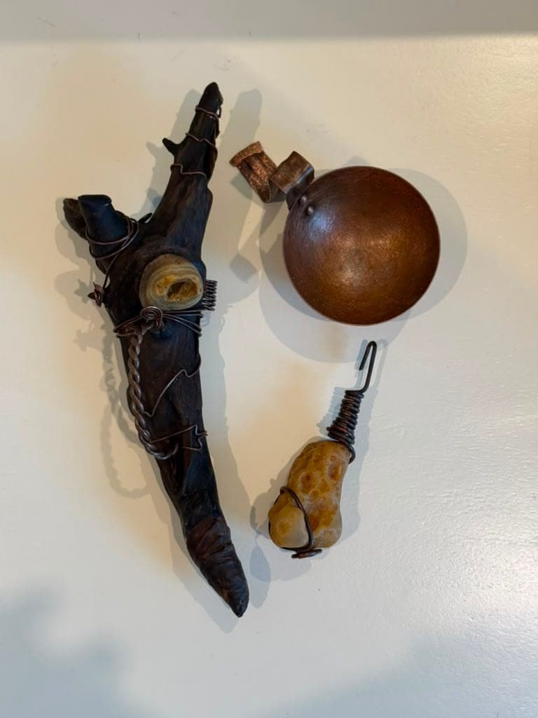 The same wand and copper pieces laid out on a pale surface, showing the wrapped copper detail and set stones up close
