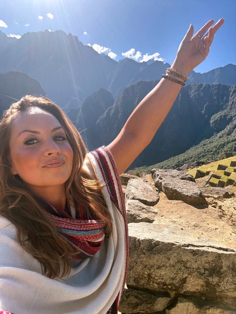 Sarah reaching toward the peaks above Machu Picchu in morning sun