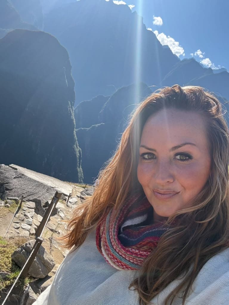 Sarah in a woven scarf with sunlight breaking over the Andes