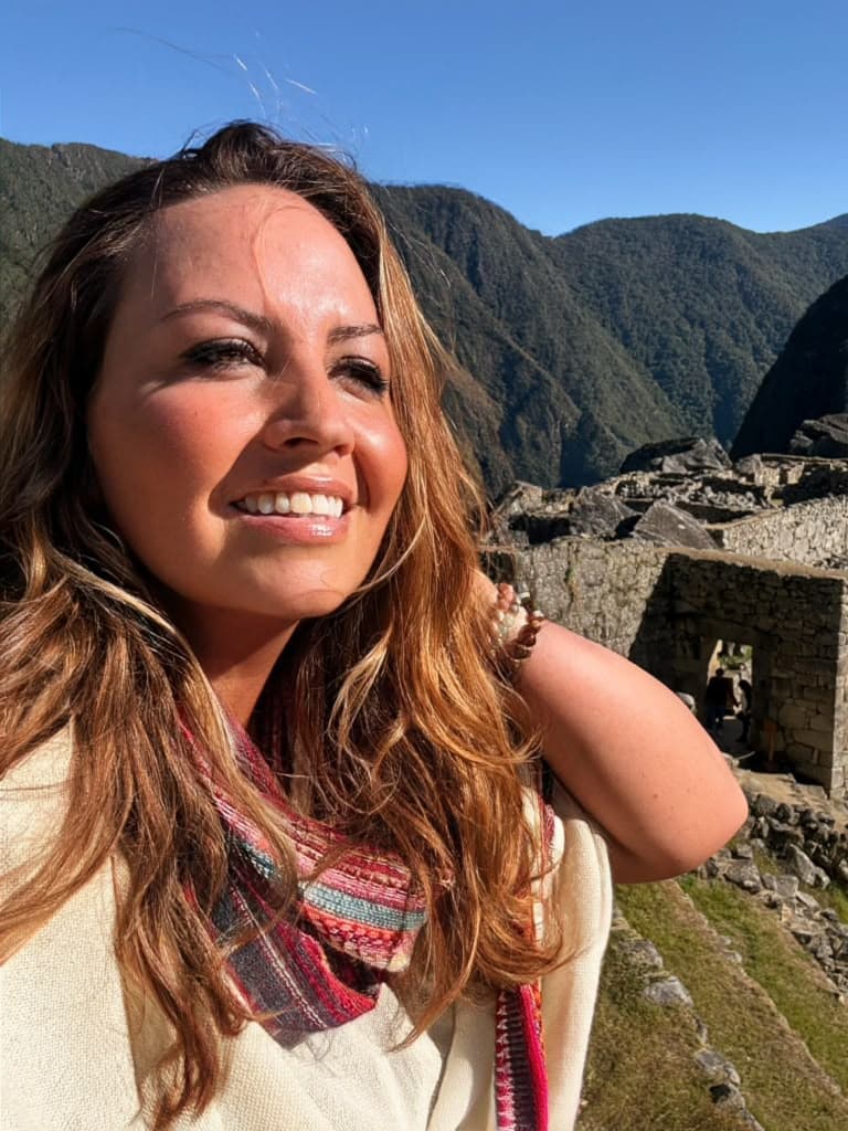 Sarah smiling in front of the stone terraces of Machu Picchu