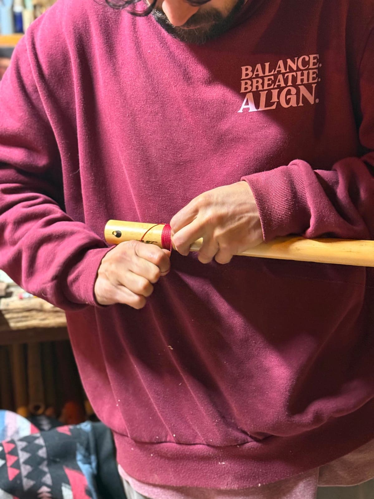 Close-up of Omar's hands wrapping a wooden flute with a red waxed cord