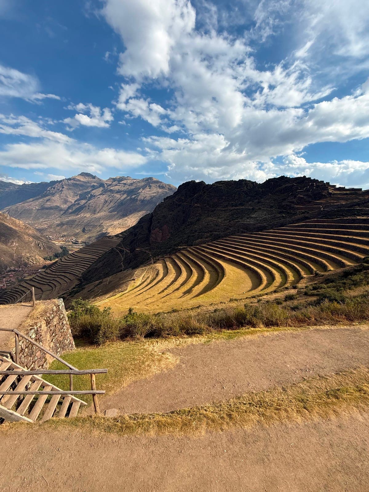 Curved Inca terraces glowing gold in the late-afternoon light, with the Sacred Valley stretching beyond